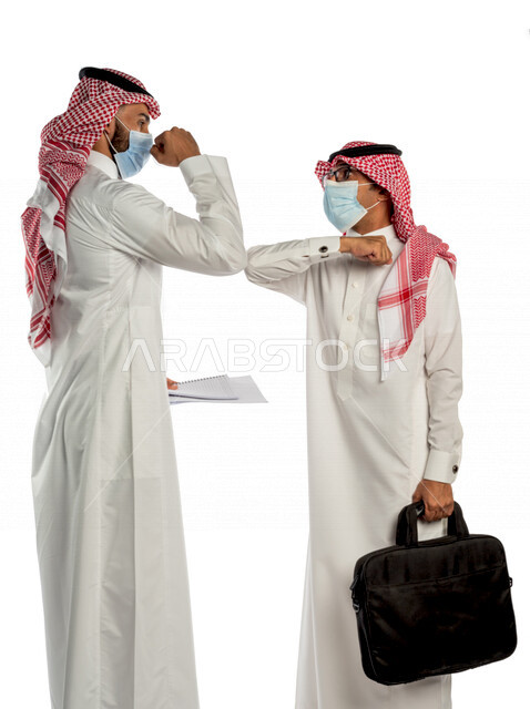 بورتريه لموظفان خليجيان سعوديان يتصافحان بإيماءات يدين مختلفة، إرتداء القناع الطبي الوقائي للوقاية من فايروس كورونا كوفيد-19، زملاء عمل، مفهوم إدارة الأعمال ، إتباع إجراءات الوقاية والحماية من الفيروسات، الحفاظ على المسافات