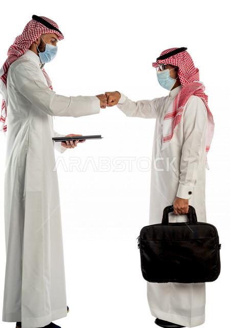 بورتريه لموظفان خليجيان سعوديان يتصافحان بإيماءات يدين مختلفة، إرتداء القناع الطبي الوقائي للوقاية من فايروس كورونا كوفيد-19، إستخدام جهاز التابلت، زملاء عمل، مفهوم إدارة الأعمال، صفقات عمل، إتباع إجراءات الوقاية والحماية من الفيروسات، الحفاظ على المسافات