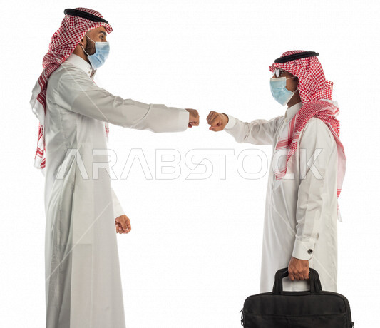بورتريه لموظفان خليجيان سعوديان يتصافحان بإيماءات يدين مختلفة، إرتداء القناع الطبي الوقائي للوقاية من فايروس كورونا كوفيد-19، زملاء عمل، مفهوم إدارة الأعمال ، إتباع إجراءات الوقاية والحماية من الفيروسات، الحفاظ على المسافات