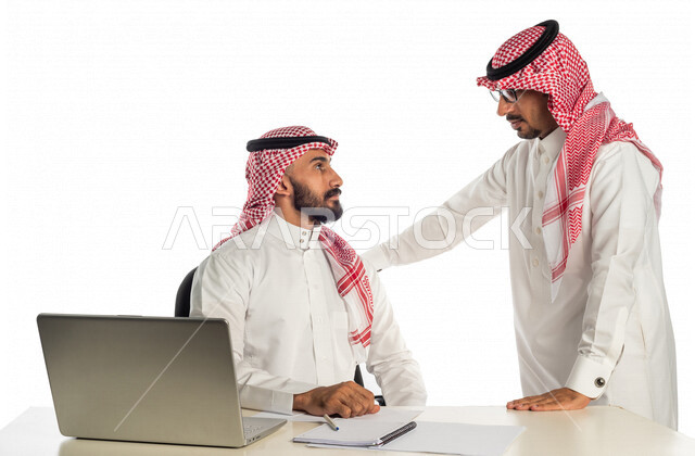 بورتريه لموظفان خليجيان سعوديان في مقر الشركة، إستخدام الحاسوب المحمول لإنجاز المهام، العمل عن بعد، زملاء عمل، شركة سعودية، أعمال تجارية، مفهوم إدارة الأعمال، تحقيق أهداف الشركة، متابعة إستراتيجية العمل، مناقشة المشروع، جلسة عمل، مراجعة البحوث العلمية