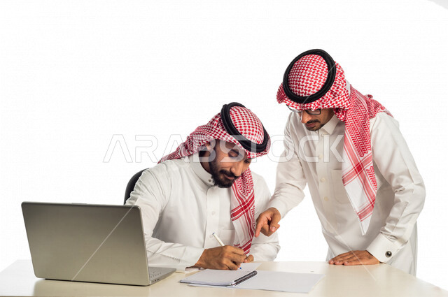 بورتريه لموظفان خليجيان سعوديان في مقر الشركة، إستخدام الحاسوب المحمول لإنجاز المهام، العمل عن بعد، زملاء عمل، شركة سعودية، أعمال تجارية، مفهوم إدارة الأعمال، تحقيق أهداف الشركة، متابعة إستراتيجية العمل، مناقشة المشروع، جلسة عمل، مراجعة البحوث العلمية