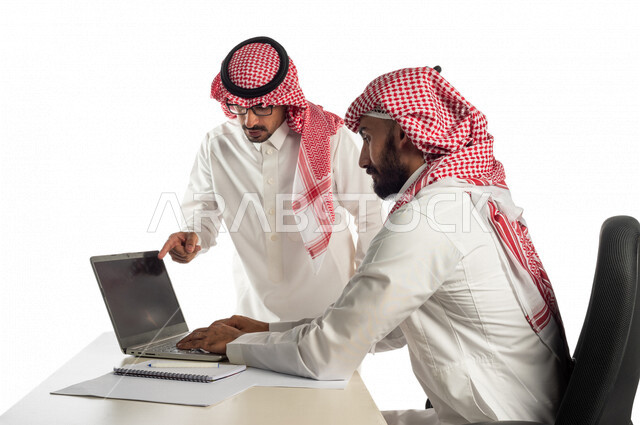 بورتريه لموظفان خليجيان سعوديان في مقر الشركة، إستخدام الحاسوب المحمول لإنجاز المهام، العمل عن بعد، زملاء عمل، شركة سعودية، أعمال تجارية، مفهوم إدارة الأعمال، تحقيق أهداف الشركة، متابعة إستراتيجية العمل، مناقشة المشروع، جلسة عمل، مراجعة البحوث العلمية