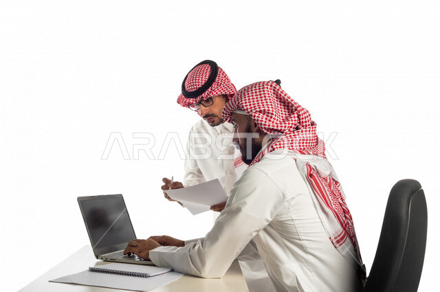 بورتريه لموظفان خليجيان سعوديان في مقر الشركة، إستخدام الحاسوب المحمول لإنجاز المهام، العمل عن بعد، زملاء عمل، شركة سعودية، أعمال تجارية، مفهوم إدارة الأعمال، تحقيق أهداف الشركة، متابعة إستراتيجية العمل، مناقشة المشروع، جلسة عمل، مراجعة البحوث العلمية