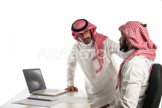 بورتريه لموظفان خليجيان سعوديان في مقر الشركة، إستخدام الحاسوب المحمول لإنجاز المهام، العمل عن بعد، زملاء عمل، شركة سعودية، أعمال تجارية، مفهوم إدارة الأعمال، تحقيق أهداف الشركة، متابعة إستراتيجية العمل، مناقشة المشروع، جلسة عمل، مراجعة البحوث العلمية