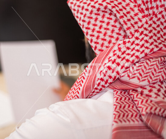 صوره من الخلف لموظف عربي سعودي خليجي  يعمل في  مقر الشركه, مناقشة وانجاز الاعمال عبر جهاز اللابتوب, تحقيق اهداف الشركه, تطوير العمل, بيئة العمل السعودي