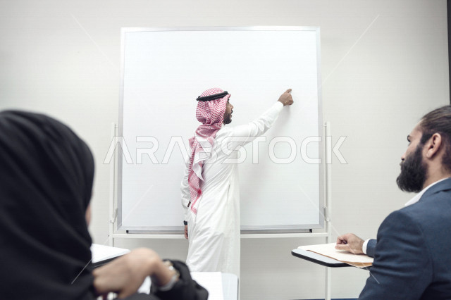 أستاذ جامعي عربي سعودي خليجي يشرح لطلابه المحاضره, مدرب جامعي, تدوين الملاحظات على السبوره, التعليم الجامعي في المملكه العربيه السعوديه, فريق عمل عربي سعودي خليجي, الإجتماع في مقر العمل, مناقشة مهام العمل, تحقيق الأهداف, تدريب الموظفين, ورشة عمل