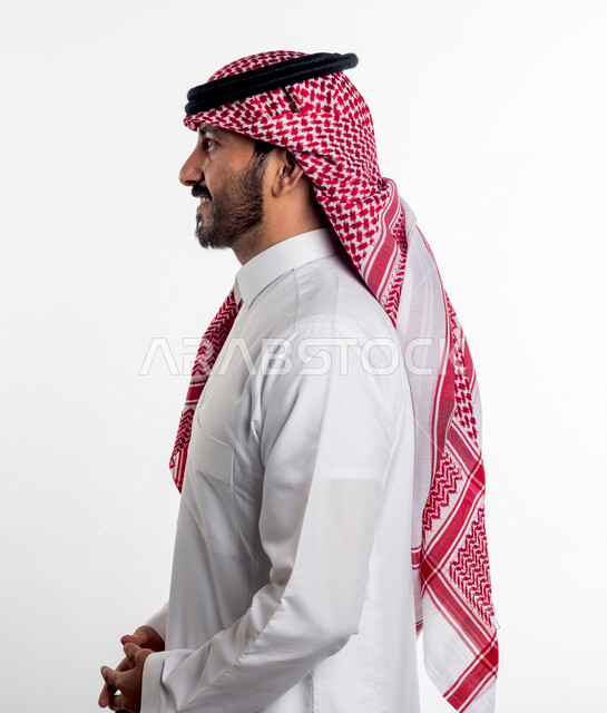 بورتريه لرجل عربي سعودي خليجي يقوم بجلسة تصوير بإيماءات وجه ، منظر جانبي لرجل سعودي يرتدي زي تقليدي سعودي مع شماغ وعقال ، خلفية بيضاء .