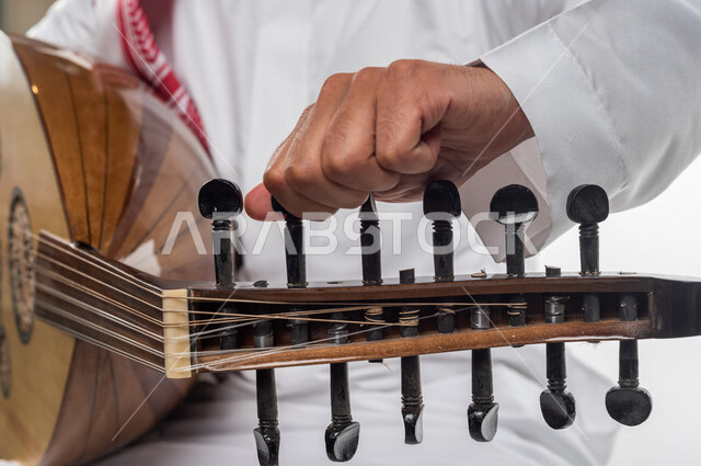 صورة مقربة لرجل عربي سعودي خليجي يعزف على آلة العود , آلات موسيقية , مواهب فنية , فنون موسيقية .