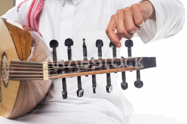 صورة مقربة لرجل عربي سعودي خليجي يعزف على آلة العود , آلات موسيقية , مواهب فنية , فنون موسيقية .