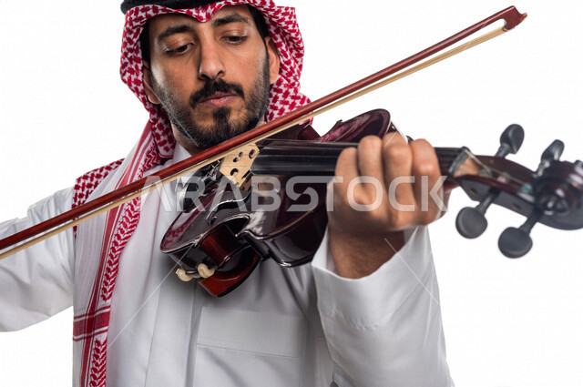 صورة مقربة لرجل عربي سعودي خليجي يعزف على آلة الكمان, آلات موسيقية ,  مواهب فنية , فنون موسيقية .