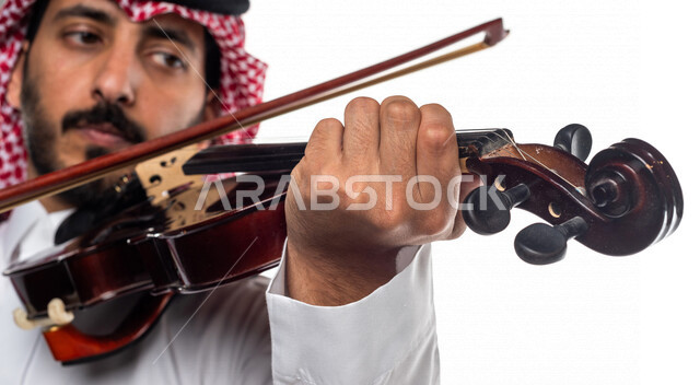 صورة مقربة لرجل عربي سعودي خليجي يعزف على آلة الكمان, آلات موسيقية ,  مواهب فنية , فنون موسيقية .