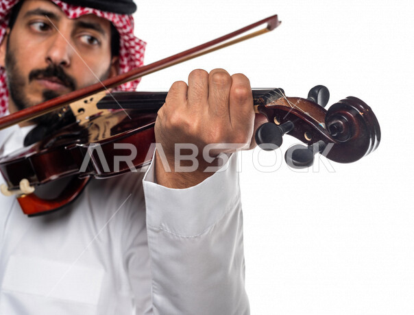 صورة مقربة لرجل عربي سعودي خليجي يعزف على آلة الكمان, آلات موسيقية ,  مواهب فنية , فنون موسيقية .