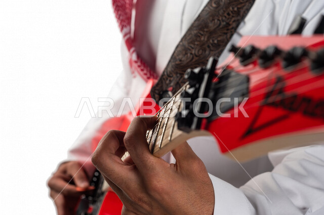 صورة مقربة لرجل عربي سعودي خليجي يقوم بالعزف على آلة الجيتار الإلكتروني , آلات موسيقية , مواهب فنية , فنون موسيقية .