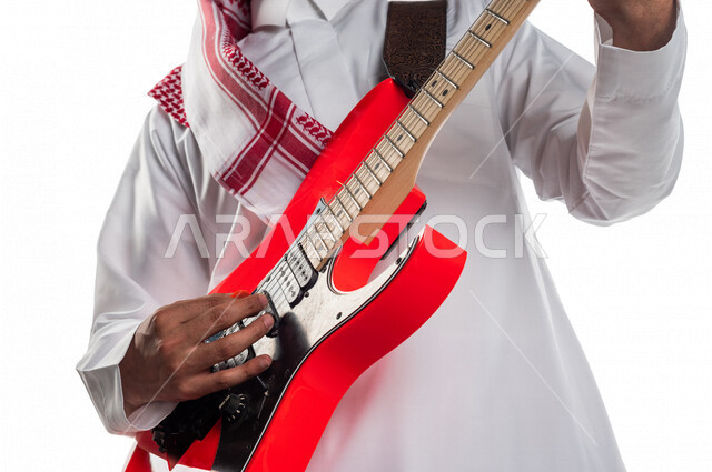 صورة مقربة لرجل عربي سعودي خليجي يقوم بالعزف على آلة الجيتار الإلكتروني , آلات موسيقية , مواهب فنية , فنون موسيقية .