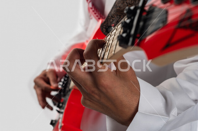 صورة مقربة لرجل عربي سعودي خليجي يقوم بالعزف على آلة الجيتار الإلكتروني , آلات موسيقية , مواهب فنية , فنون موسيقية .