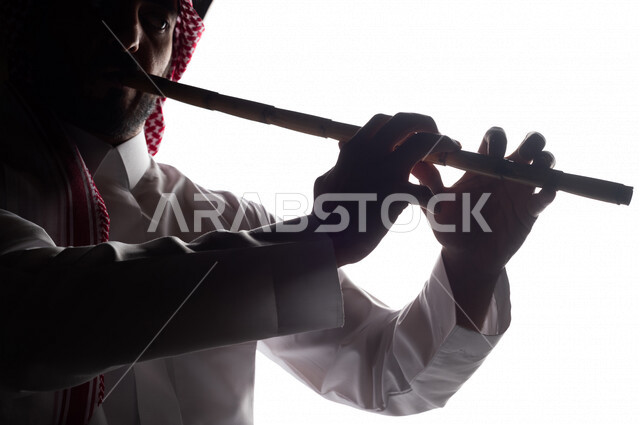 صورة ظلية لرجل عربي سعودي خليجي يقوم بالعزف على آلة الناي , آلات موسيقية , بورتريه لشاب يمارس هواية العزف , مواهب فنية , فنون موسيقية .