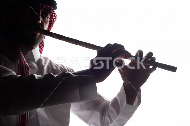 صورة ظلية لرجل عربي سعودي خليجي يقوم بالعزف على آلة الناي , آلات موسيقية , بورتريه لشاب يمارس هواية العزف , مواهب فنية , فنون موسيقية .