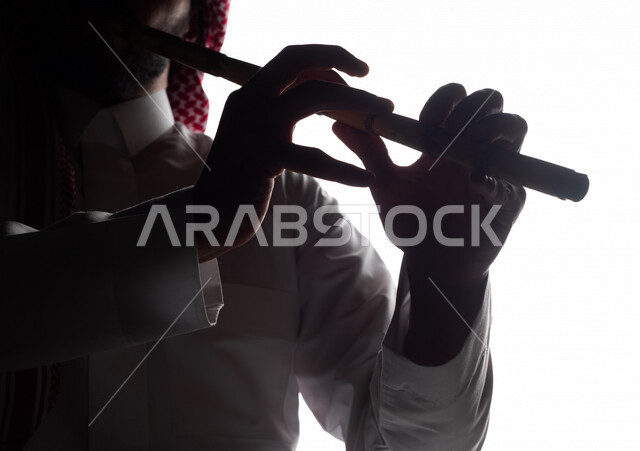 صورة ظلية لرجل عربي سعودي خليجي يقوم بالعزف على آلة الناي , آلات موسيقية , بورتريه لشاب يمارس هواية العزف , مواهب فنية , فنون موسيقية .