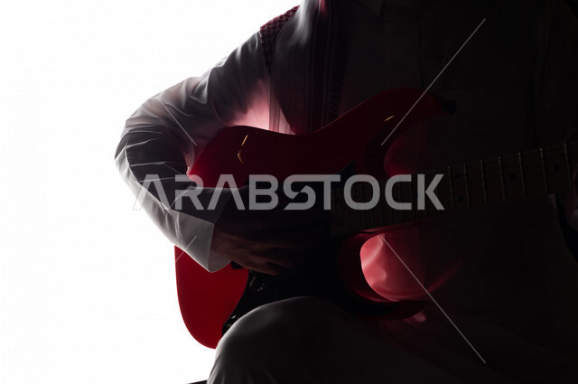 صورة ظلية لرجل عربي سعودي خليجي يقوم بالعزف على آلة القيثارة , آلات موسيقية , بورتريه لشاب يمارس هواية العزف , فنون موسيقية , مواهب فنية.