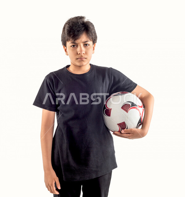 بورتريه لطفل عربي خليجي سعودي يحمل كرة قدم تحت ذراعه، مشجع لفريق سعودي لكرة القدم، ايماءات وجه ويدين تدل على الغضب، خلفية بيضاء