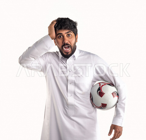 بورتريه لشاب عربي خليجي سعودي يحمل كرة قدم تحت ذراعه، تشجيع فريق كرة قدم، إيماءات وجه ويدين تدل على الحزن والدهشة والخذلان، خلفية بيضاء