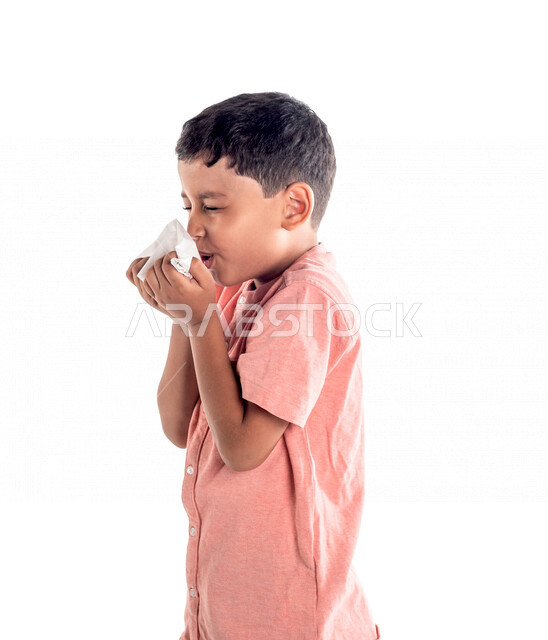 Portrait of a Saudi Arabian Gulf boy using a tissue to prevent a runny nose, suffering from colds and allergies, colds, white background