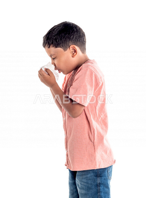 بورتريه لفتى عربي خليجي سعودي يستخدام المنديل لمنع سيلان الانف، يعاني من الزكام والحساسية ، نزلات البرد،  خلفية بيضاء