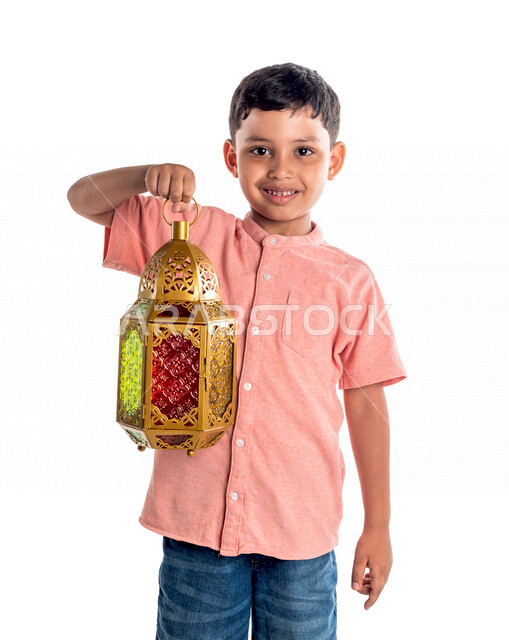Portrait of a smiling and happy Saudi Gulf boy, holding a Ramadan lantern in his hand, Ramadan Kareem, the month of worship, white background
