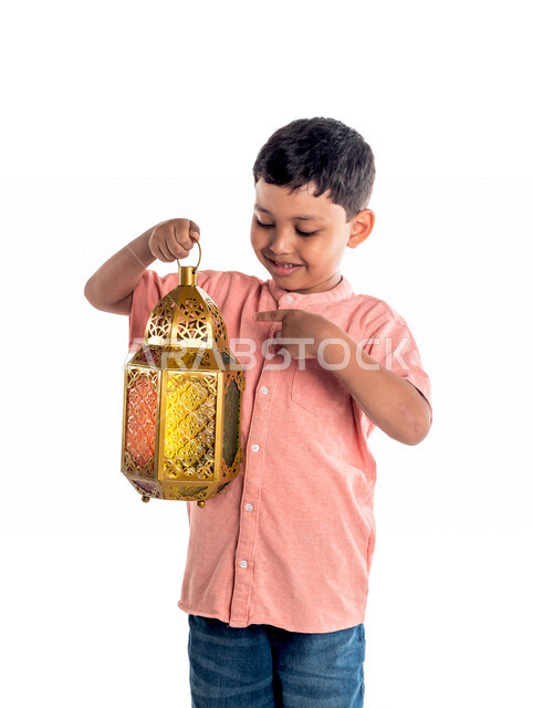 Portrait of a smiling and happy Saudi Gulf boy, holding a Ramadan lantern in his hand, Ramadan Kareem, the month of worship, white background