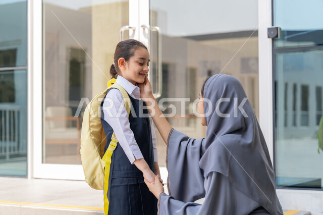 مرافقة الأولاد إلى المدرسة لتعزيز الأمان والاطمئنان لديهم, تقديم الحب والدعم النفسي والمعنوي للأبناء, إسداء النصائح والتشجيع والحماس, تلميذة عربية خليجية إماراتية ترتدي الزي المدرسي وتحمل حقيبة الظهر تقف برفقة والدتها لتودعها في أول أيام الفصل الدراسي الجديد