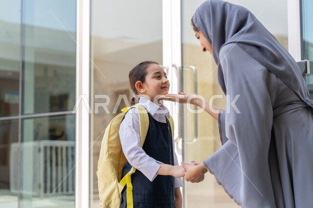إسداء النصائح والتشجيع والحماس, مرافقة الأولاد إلى المدرسة لتعزيز الأمان والاطمئنان لديهم, تقديم الحب والدعم النفسي والمعنوي للأبناء, تلميذة عربية خليجية إماراتية ترتدي الزي المدرسي وتحمل حقيبة الظهر تقف برفقة والدتها لتودعها في أول أيام الفصل الدراسي الجديد