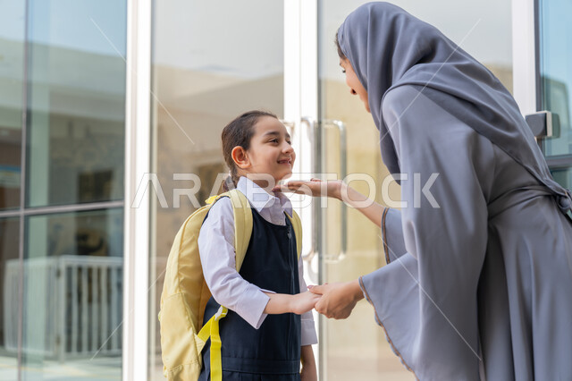 تقديم الحب والدعم النفسي والمعنوي للأبناء, إسداء النصائح والتشجيع والحماس, تلميذة عربية خليجية إماراتية ترتدي الزي المدرسي وتحمل حقيبة الظهر تقف برفقة والدتها لتودعها في أول أيام الفصل الدراسي الجديد, مرافقة الأولاد إلى المدرسة لتعزيز الأمان والاطمئنان لديهم