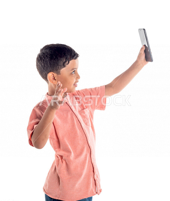 Portrait of a Saudi Arabian Gulf boy using a mobile phone, taking a selfie, making a video call, white background