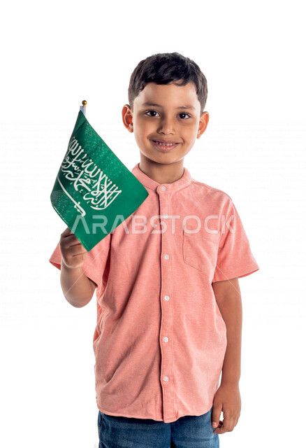 Portrait of a Saudi Arabian Gulf boy holding the flag of Saudi Arabia, celebrating Saudi National Day, white background