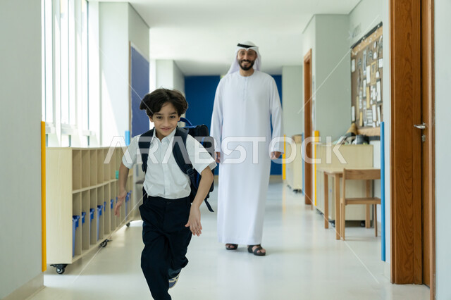 الانطلاق بسعادة وحماس نحو الفصل المخصص، تشجيع الأولاد وتقديم الدعم المعنوي لهم في بداية السنة الدراسية، الحضور المبكر للحصص المدرسية، أب عربي خليجي إماراتي يرتدي الكندورة والغترة يرافق ابنه إلى المدرسة في يومه الدراسي الأول، تلميذ مرتب يحمل حقيبة الظهر بفرح