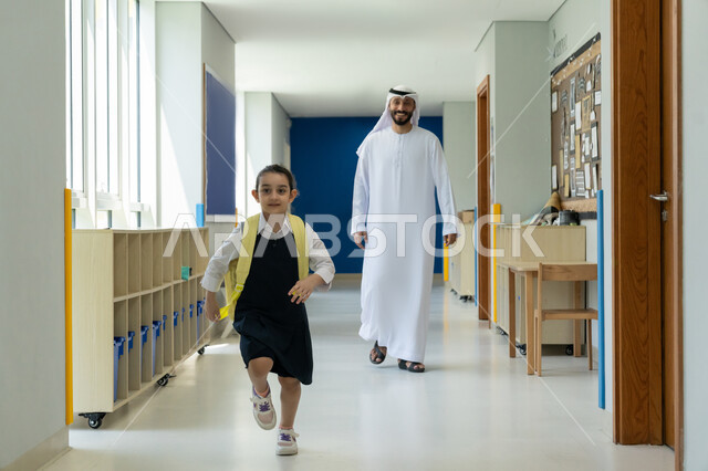 السعادة والحماس بالعودة إلى المدرسة، رعاية الأولاد وتقديم الدعم والتشجيع لهم في بداية السنة الدراسية، الحضور المبكر للحصص المدرسية، أب عربي خليجي إماراتي يرتدي الكندورة والغترة يرافق ابنته إلى المدرسة في يومها الدراسي الأول، تلميذة مرتبة تحمل حقيبة الظهر بفرح