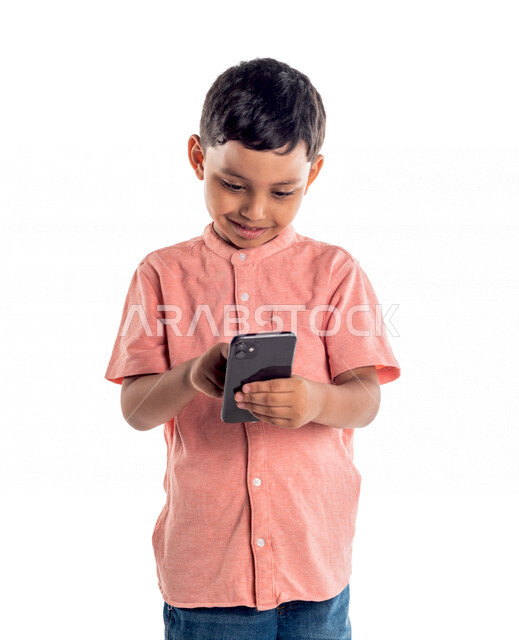 Portrait of a Saudi Arabian Gulf boy using a mobile phone, electronic games, watching video, white background