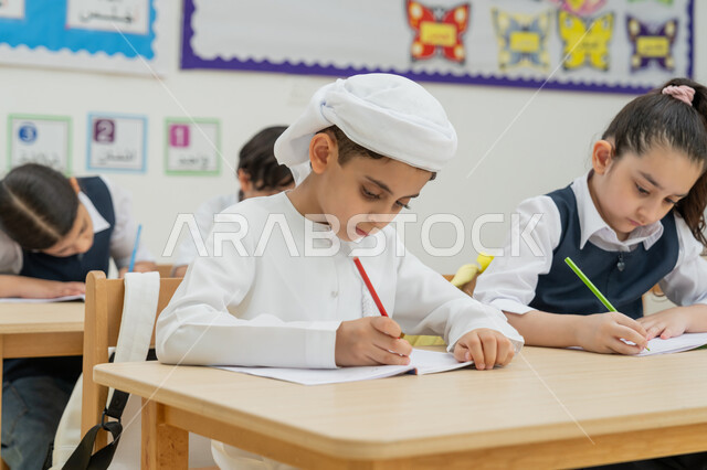 Developing creative skills, the concept of diligence and excellence, modern learning methods, back-to-school season, goals of education in the Kingdom of Saudi Arabia, Arab Gulf Emirati students sitting on desks in the classroom and writing their homework