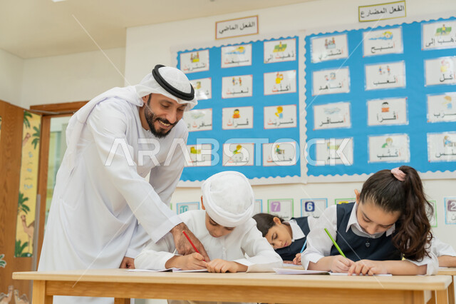 ايماءات التركيز والتمعن والتركيز، التربية والتعليم في الامارات العربية المتحدة، معلم عربي خليجي إماراتي يرتدي الكندورة والغترة يقوم بمساعدة الطلاب اثناء تقديم الامتحانات، مفهوم الاجتهاد وطلب التفوق، أهمية العلم في تنمية القدرات العقلية