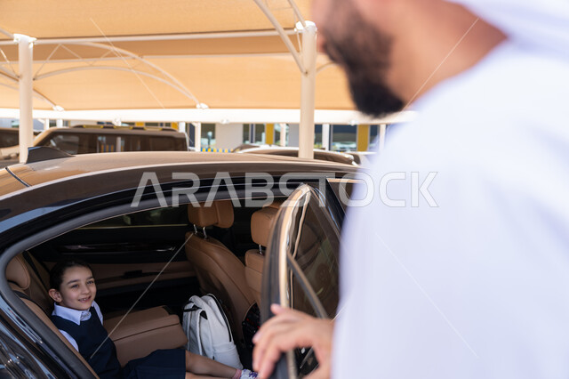 الحضور المبكر للحصص المدرسية, الاهتمام بتعليم وتطوير الابناء ودعمهم، اب عربي خليجي إماراتي يرتدي الكندورة والغترة يقوم بتوديع ابنته قبل ركوب السيارة، تلميذة متفوقة تستعد للذهاب الى المدرسة بإيماءات الحماس والسرور، التعليم الحديث في الامارات