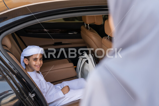 الحضور المبكر للحصص المدرسية، الاهتمام بتعليم وتطوير الابناء ودعمهم، ام عربية خليجية إماراتية تقوم بتوديع ابنها قبل ركوب السيارة، تلميذ متفوق يرتدي الكندورة والعمامة البيضاء يستعد للذهاب الى المدرسة بإيماءات الحماس والسرور، التعليم الحديث في الامارات