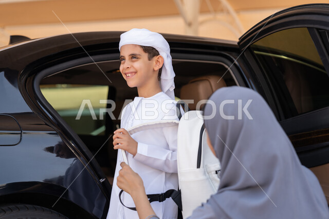 التعليم الحديث في الامارات، الحضور المبكر للحصص المدرسية، الاهتمام بتعليم وتطوير الابناء ودعمهم، ام عربية خليجية إماراتية تقوم بتوديع ابنها قبل ركوب السيارة، تلميذ متفوق يرتدي الكندورة والعمامة البيضاء يستعد للذهاب الى المدرسة بإيماءات الحماس والسرور
