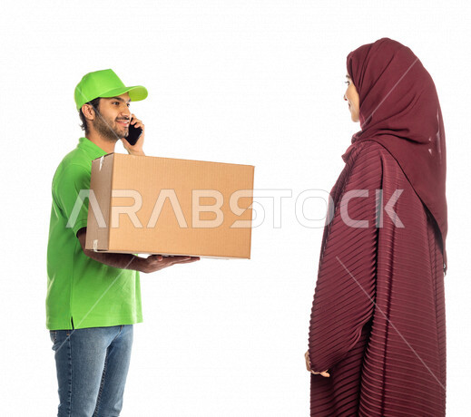 بورتريه لرجل عربي سعودي خليجي يرتدي قبعه خضراء يقوم بتسليم البضائع للزبائن, امراه عربيه سعوديه خليجيه تستلم مشترياتها, التسوق الالكتروني, طلبات اونلاين, التسوق الذكي, عملية شحن وتوصيل موثوقه, مندوب توصيل, امين مخازن, اجراء مكالمه هاتفيه لتأكيد الحجوزات وا