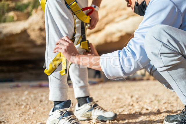A Saudi Arabian Gulf youth, preparing and preparing the necessary equipment for mountain climbing, hiking, mountain stones and rocks, health and fitness