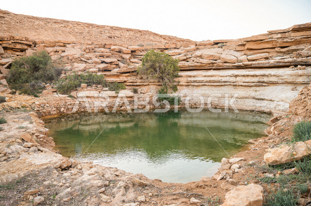 Aesthetic image of a lake in the middle of rocky mountains in Saudi Arabia, a beautiful landscape in broad daylight, mountains, trees and rocks, the beauty of landscapes in Saudi Arabia