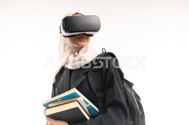 Virtual world simulation, integration of modern technologies with learning and training, education using virtual world technology, close-up portrait of a veiled Saudi Arabian Gulf university student wearing a backpack, 3D VR glasses, holding a set of books in her hand, white background