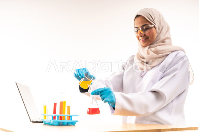 Searching for chemical reaction results, using test tubes to conduct scientific experiments, close-up portrait of smiling Saudi Arabian Gulf student wearing white coat and glasses sitting in laboratory, integrating education with technology and technology, biochemistry concept, white background