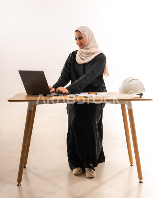 المناهج والمواد التعليمية، التعليم الجامعي في السعودية، بورتريه لطالبة جامعية عربية خليجية سعودية محجبة ترتدي العباءة تدرس في قسم الهندسة والانشاء, تدقيق وتصميم المشروع الهندسي, دمج التكنولوجيا في المجال التعليمي, الدراسة والاجتهاد والتفوق, خلفية بيضاء
