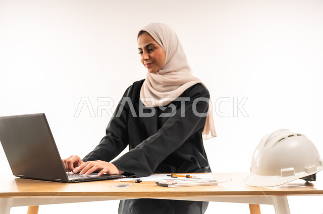 الدراسة والاجتهاد والتفوق, المناهج والمواد التعليمية، التعليم الجامعي في السعودية، بورتريه لطالبة جامعية عربية خليجية سعودية محجبة ترتدي العباءة تدرس في قسم الهندسة والانشاء, تدقيق وتصميم المشروع الهندسي, دمج التكنولوجيا في المجال التعليمي, خلفية بيضاء