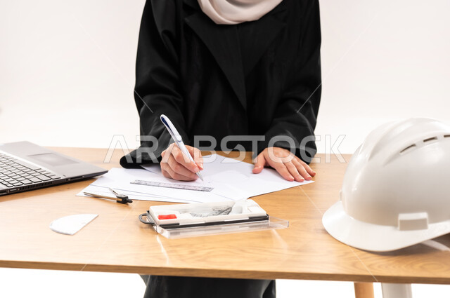 المناهج والمواد التعليمية, بورتريه مقرب لطالبة جامعية عربية خليجية سعودية محجبة ترتدي العباءة تجلس على الطاولة وتقوم بمراجعة المشروع الهندسي، دمج التقنيات الحديثة والتكنولوجيا بالتعليم الأكاديمي, مفهوم الاجتهاد والتفوق, خلفية بيضاء